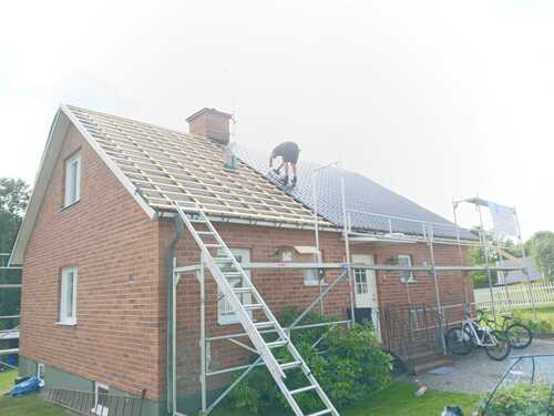 Takarbete på tegelhus med byggställning och stege