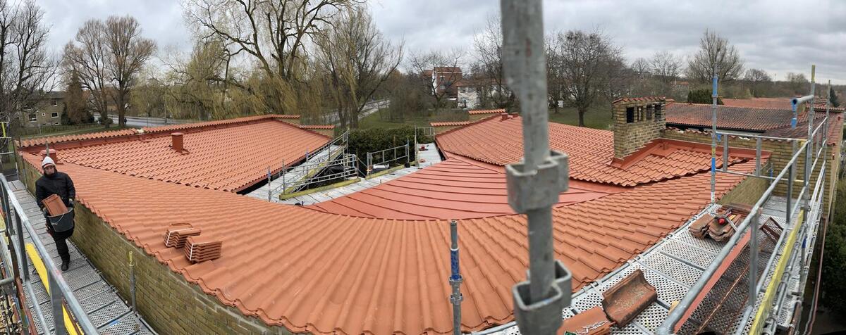 Färdiglagt tak med röda tegelpannor och rökgångar på villa i Skåne