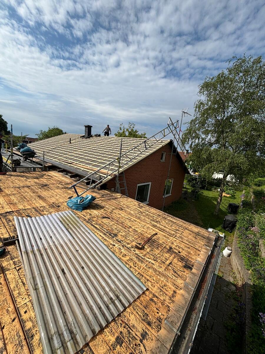 Pågående rivning av gammalt tak med synlig råspont och korrugerad plåt på villa