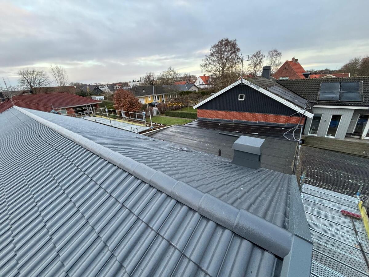 Färdiglagt tak med grå korrugerad plåt på kommersiell fastighet med ventilationsdetaljer