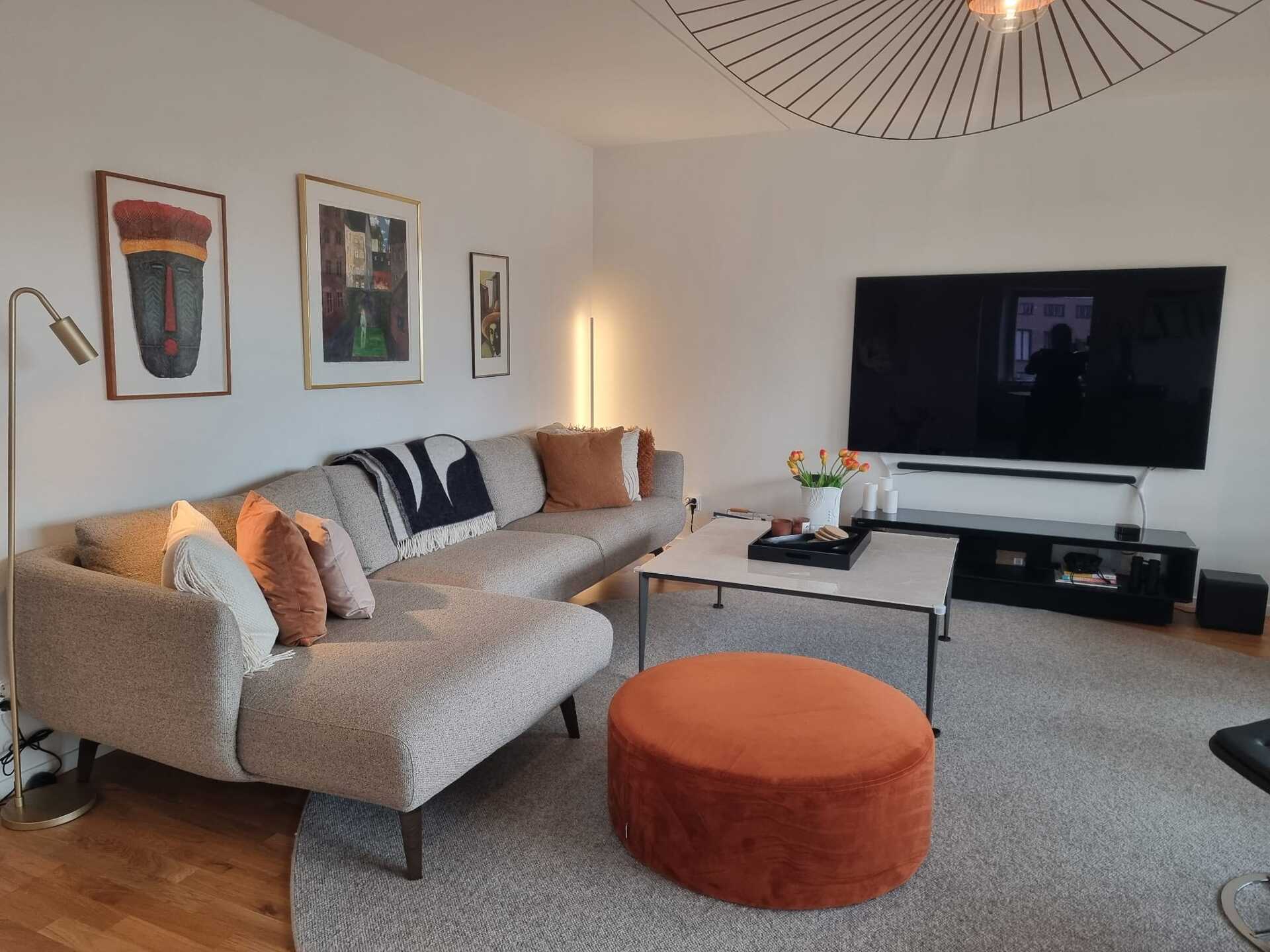 Städat och välkomnande vardagsrum med soffa, soffbord och stor TV på väggen
