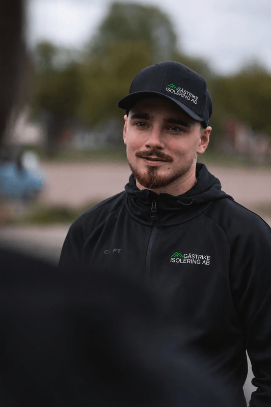 Montör från Gästrike Isolering AB i svart arbetsjacka med logotyp