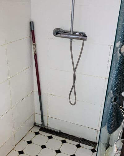 Duschblandare med slang i kaklat badrum före renovering