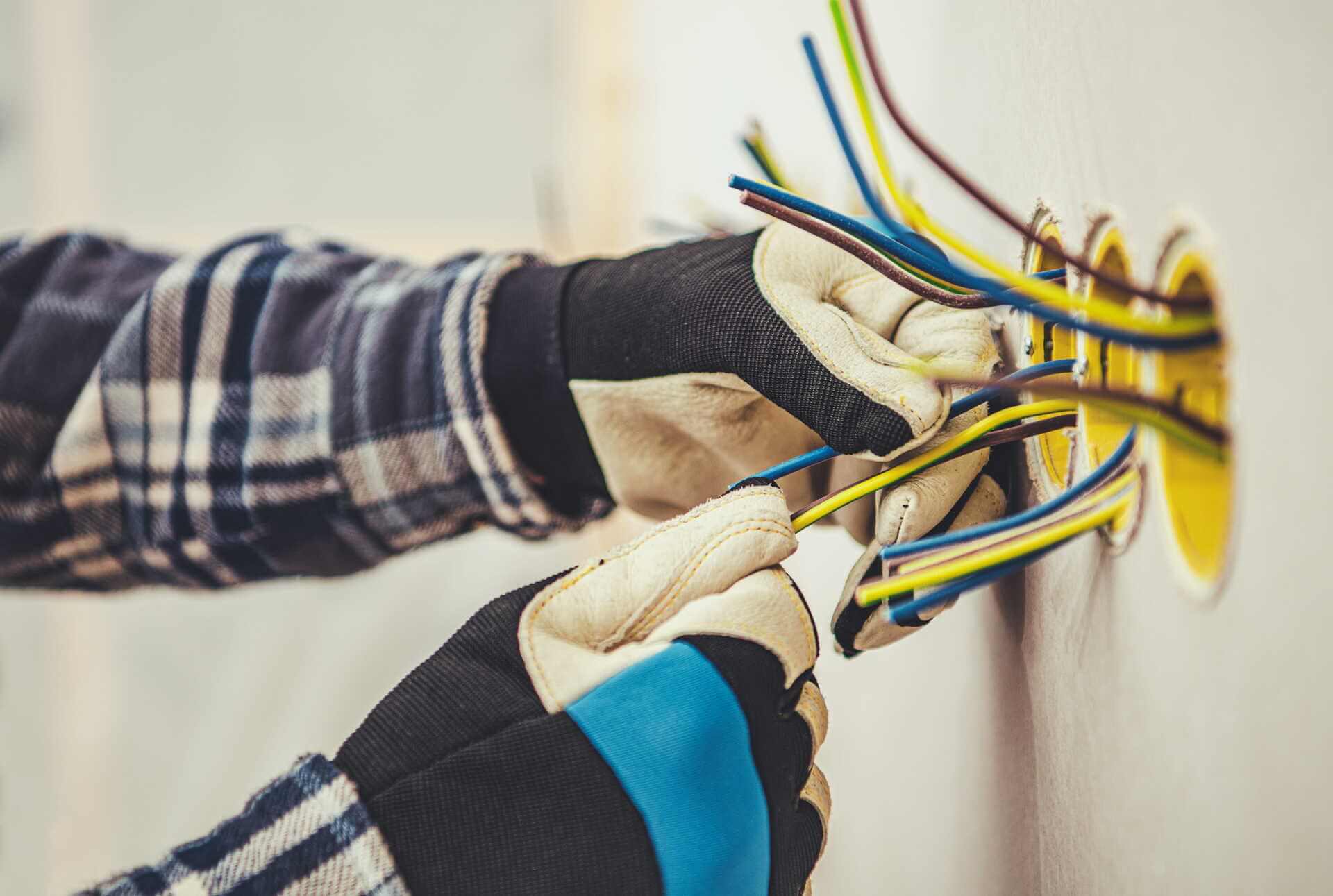 Elektriker med handskar kopplar elkablar i vägg