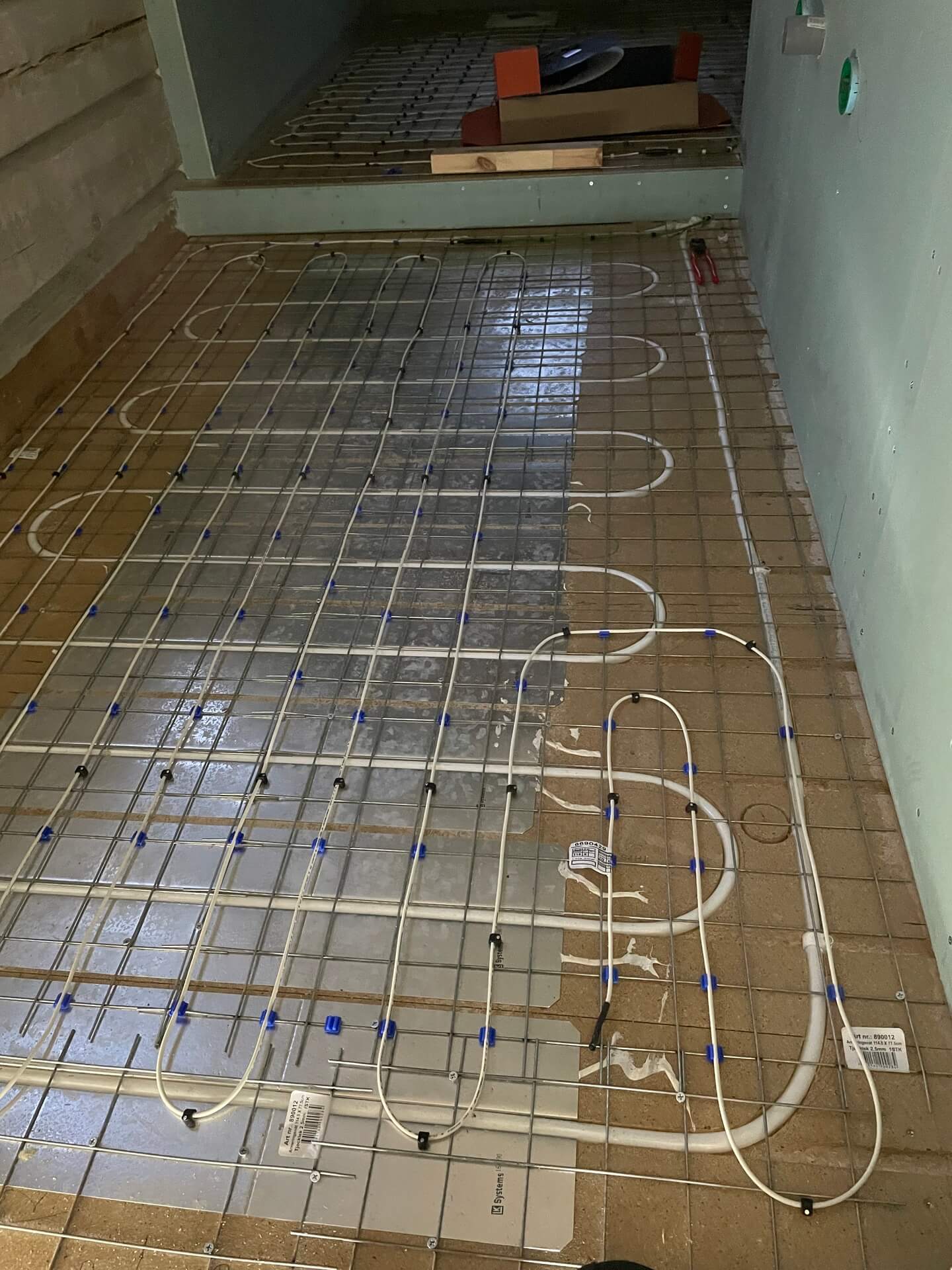 Golvvärme med elkablar ingjutna i kakelgolv under installation