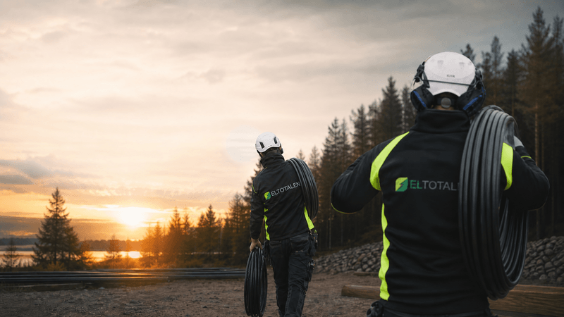 Eltotalens elektriker med kabelrulle i solnedgång