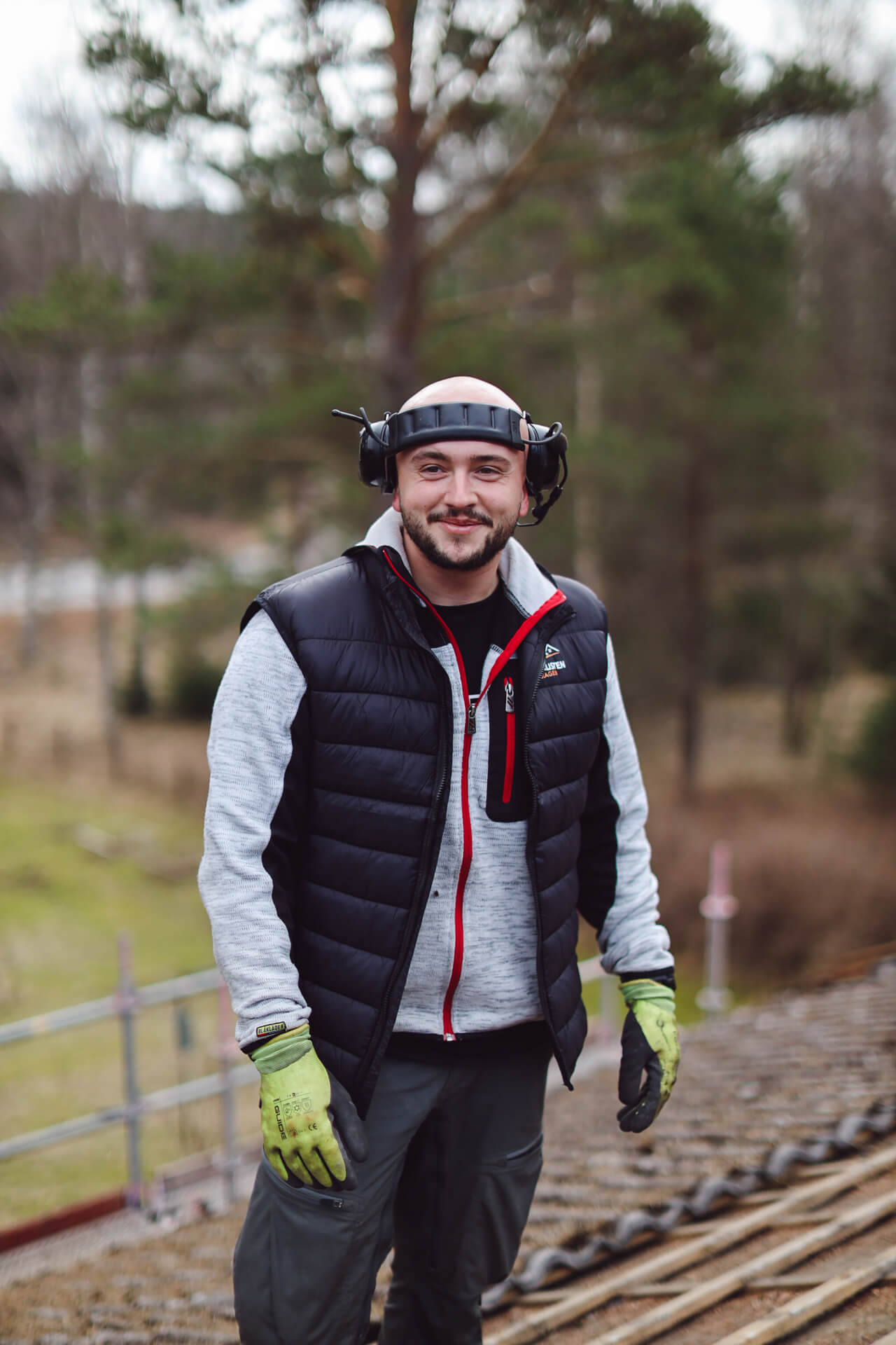 Person med arbetskläder och hörselskydd utomhus