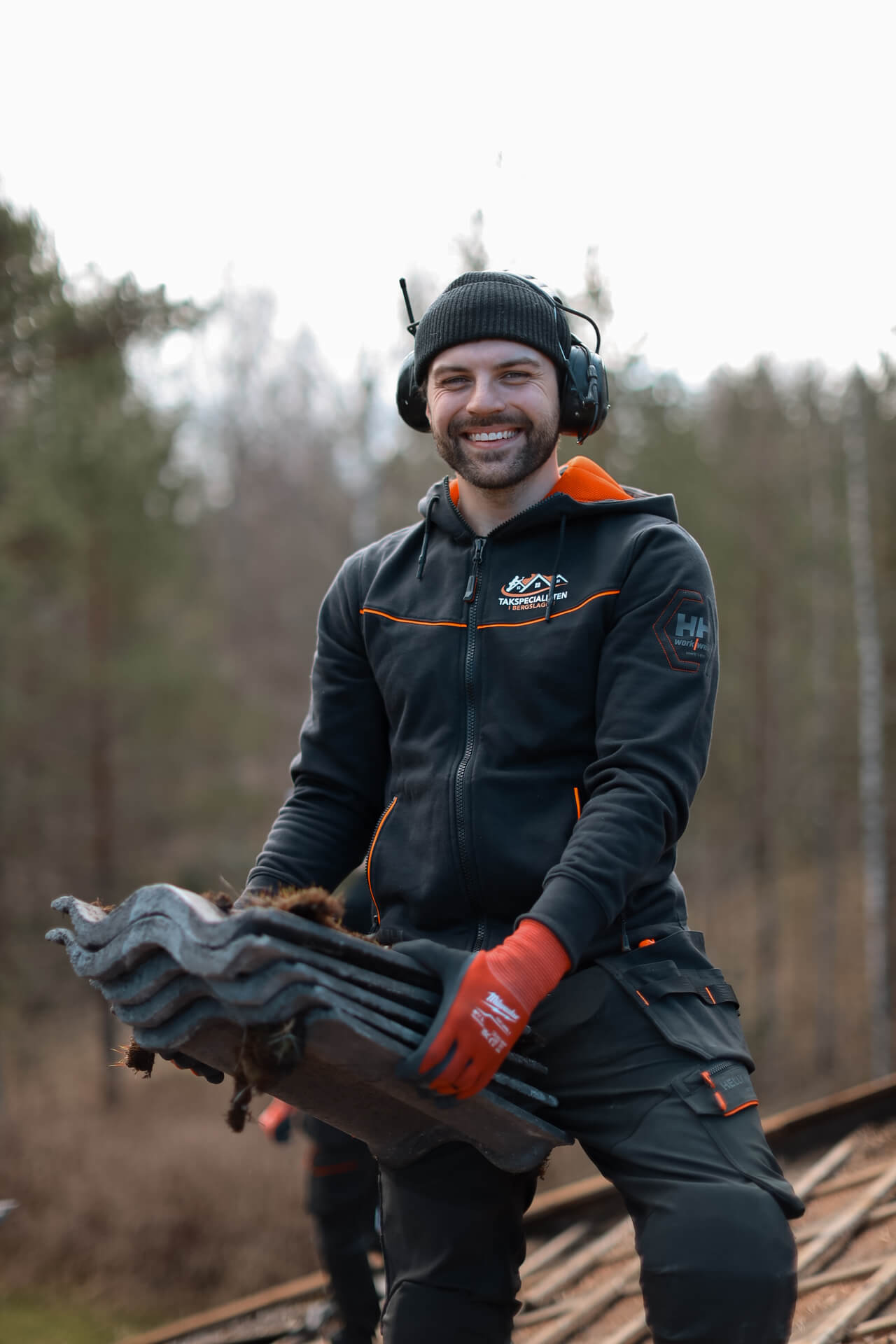 Person som bär takpannor under takarbete