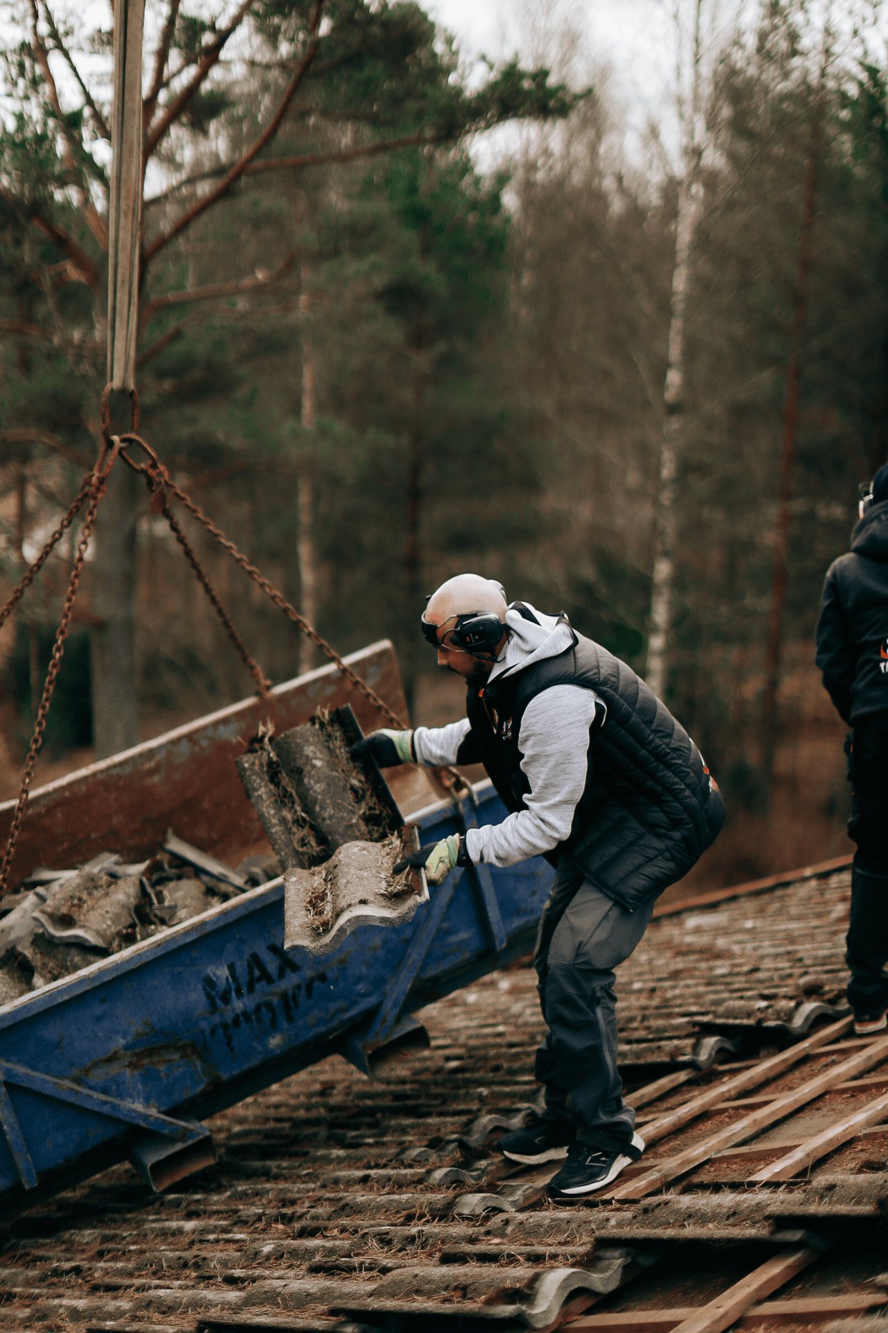 Takarbetare som lastar takpannor i en container