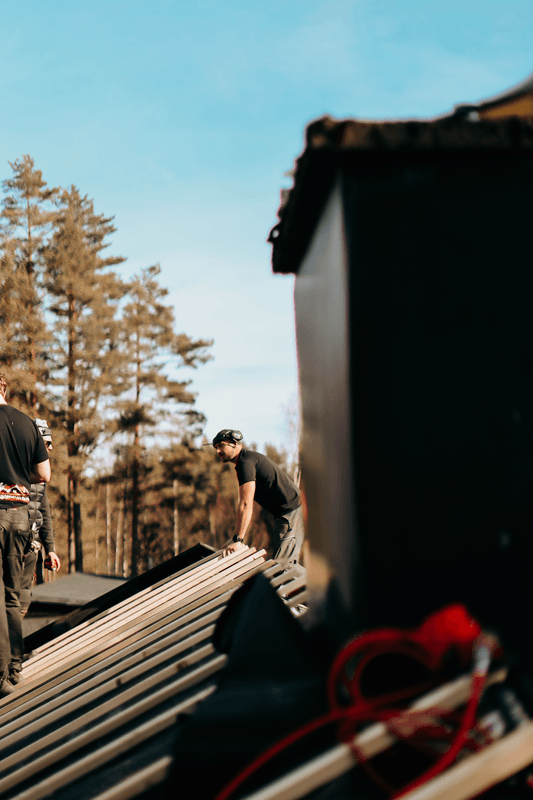 Hantverkare som bär byggmaterial vid takarbete