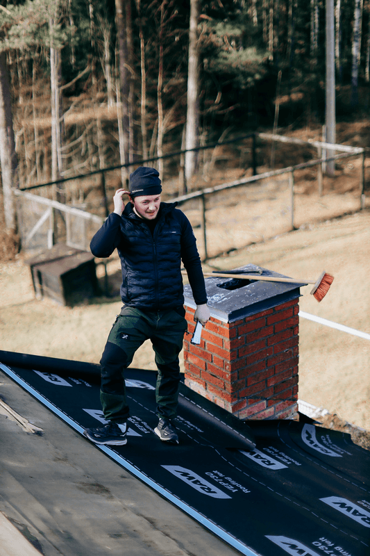 Person som arbetar vid skorsten på ett hustak