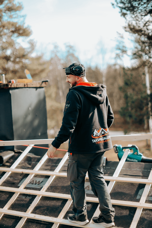 Hantverkare med byggmaterial på ett hustak