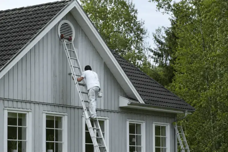 Bild på målare som klättrar upp för stege