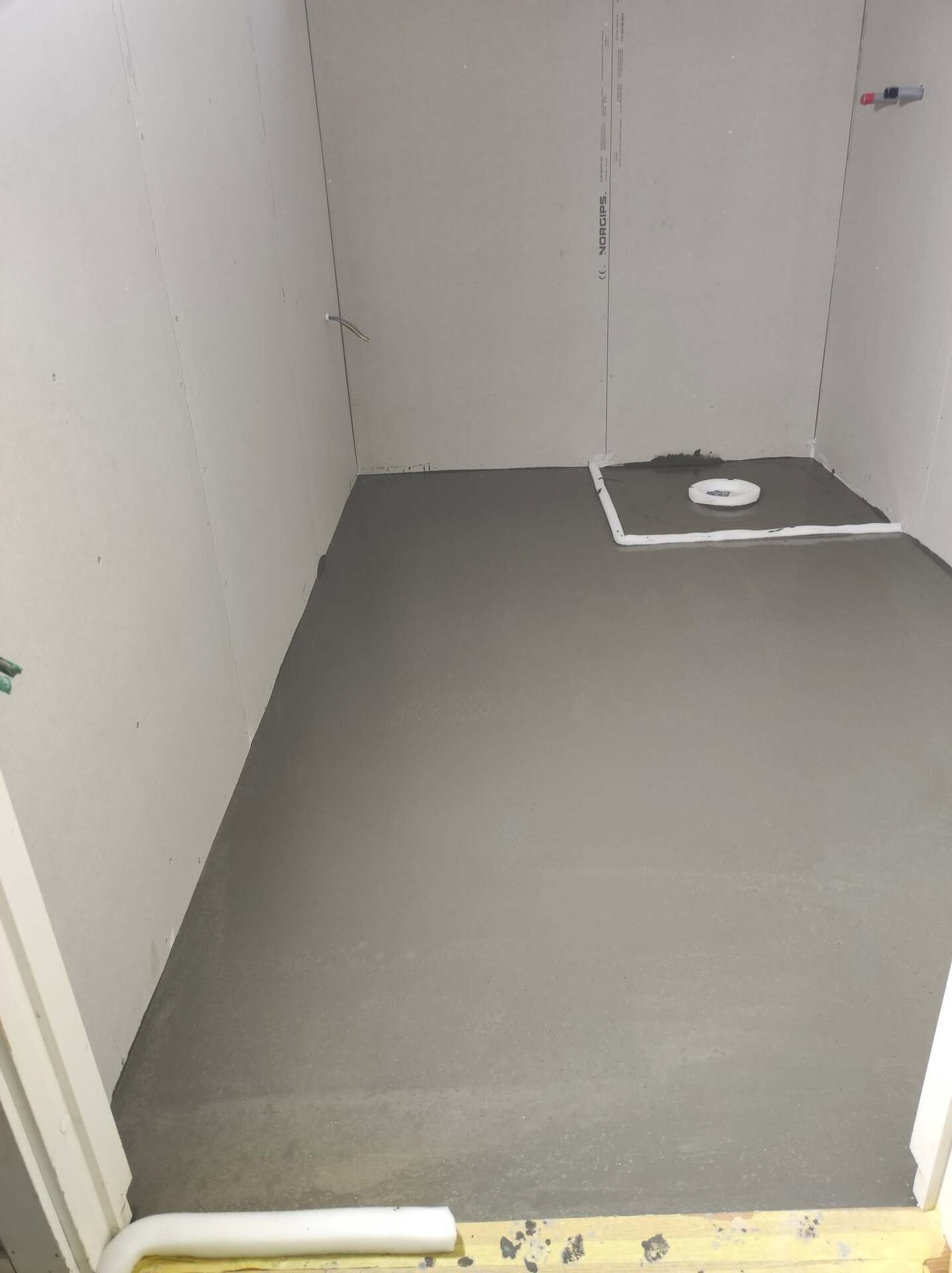 Nylagt betonggolv med golvbrunn inför plattsättning i badrum