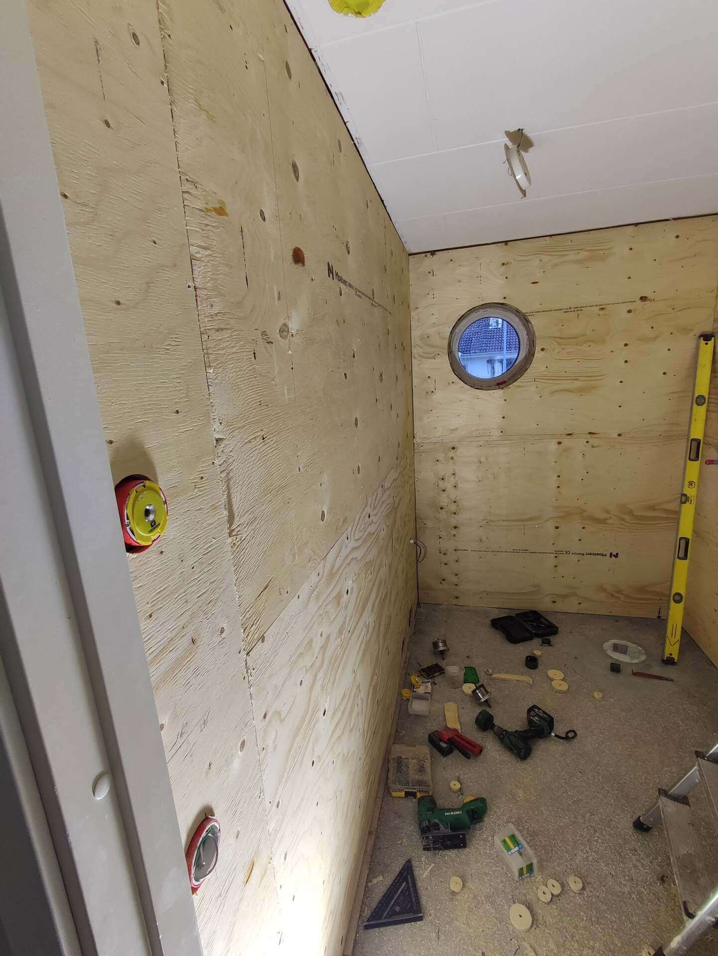 Badrum under renovering med spånskiva på väggar och runt fönster