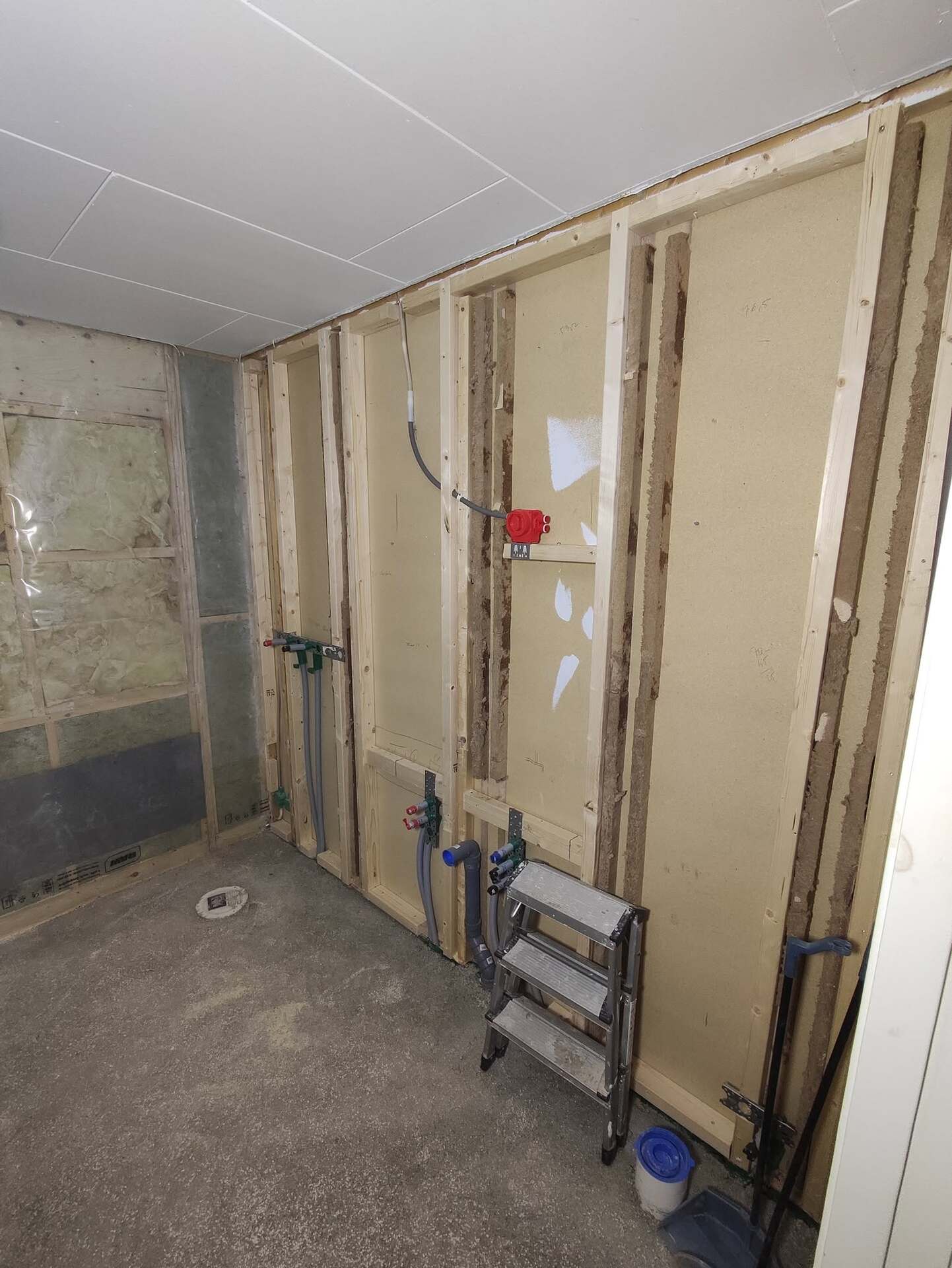 Badrum under renovering med reglar, rördragning och isolering före väggmontering