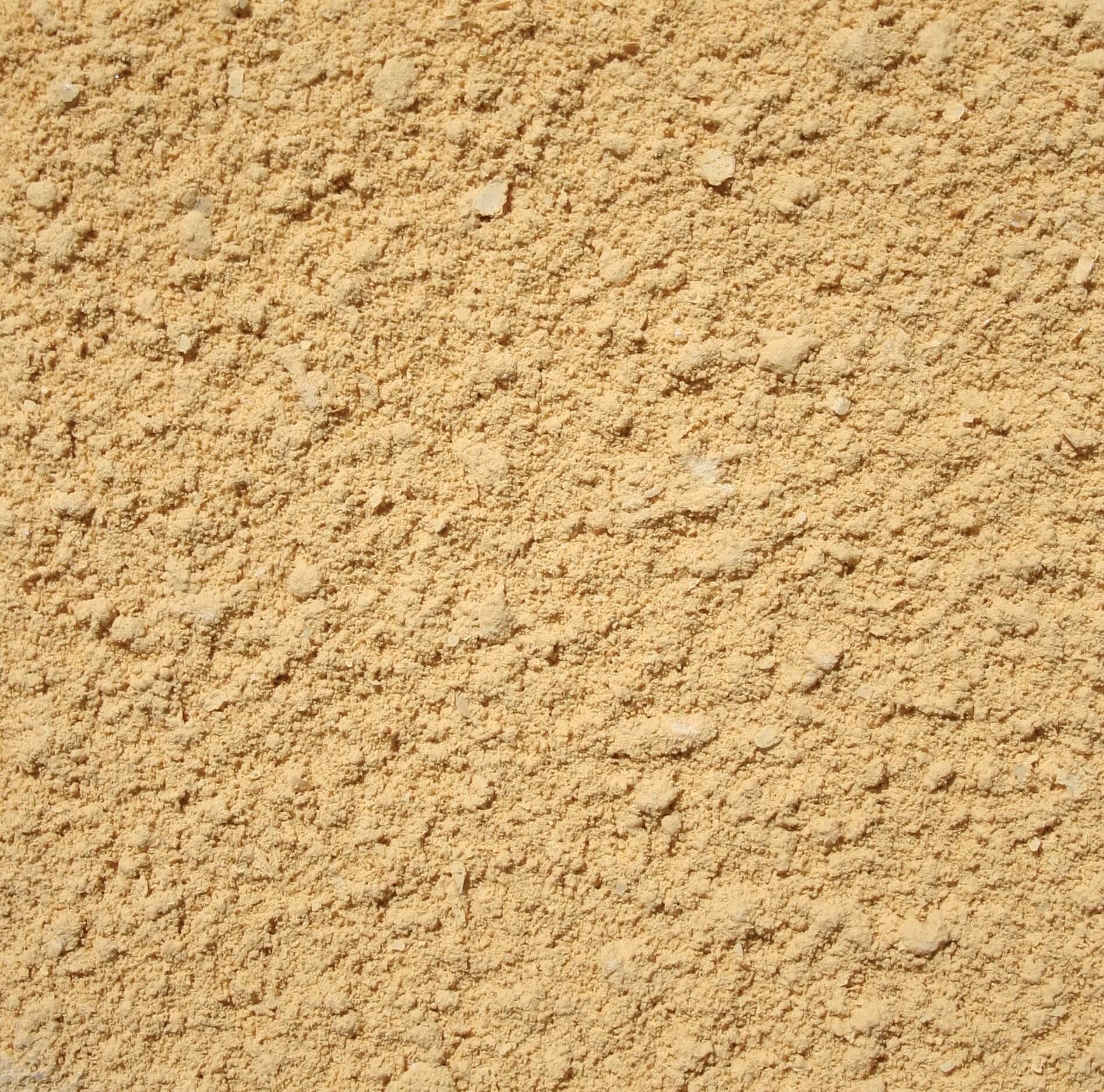 Närbild på putsfasad med grov struktur i gulbeige kulör