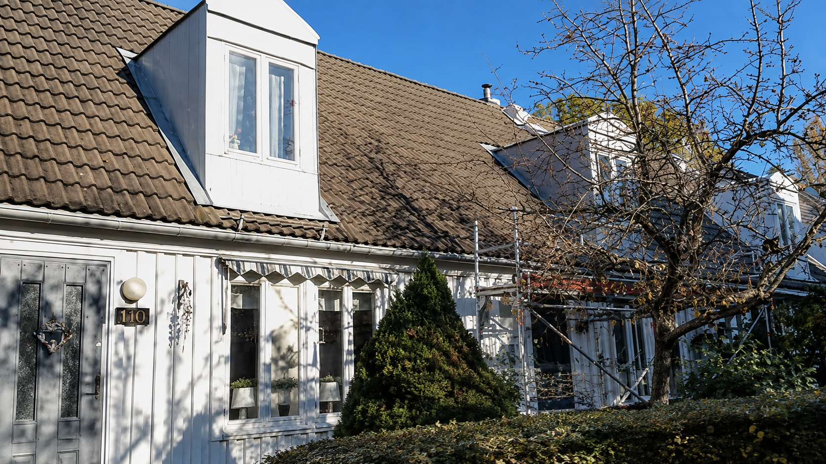 Vitt hus med takkupa och äldre tegeltak