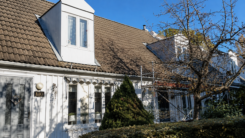 Vitt hus med takkupa och äldre tegeltak