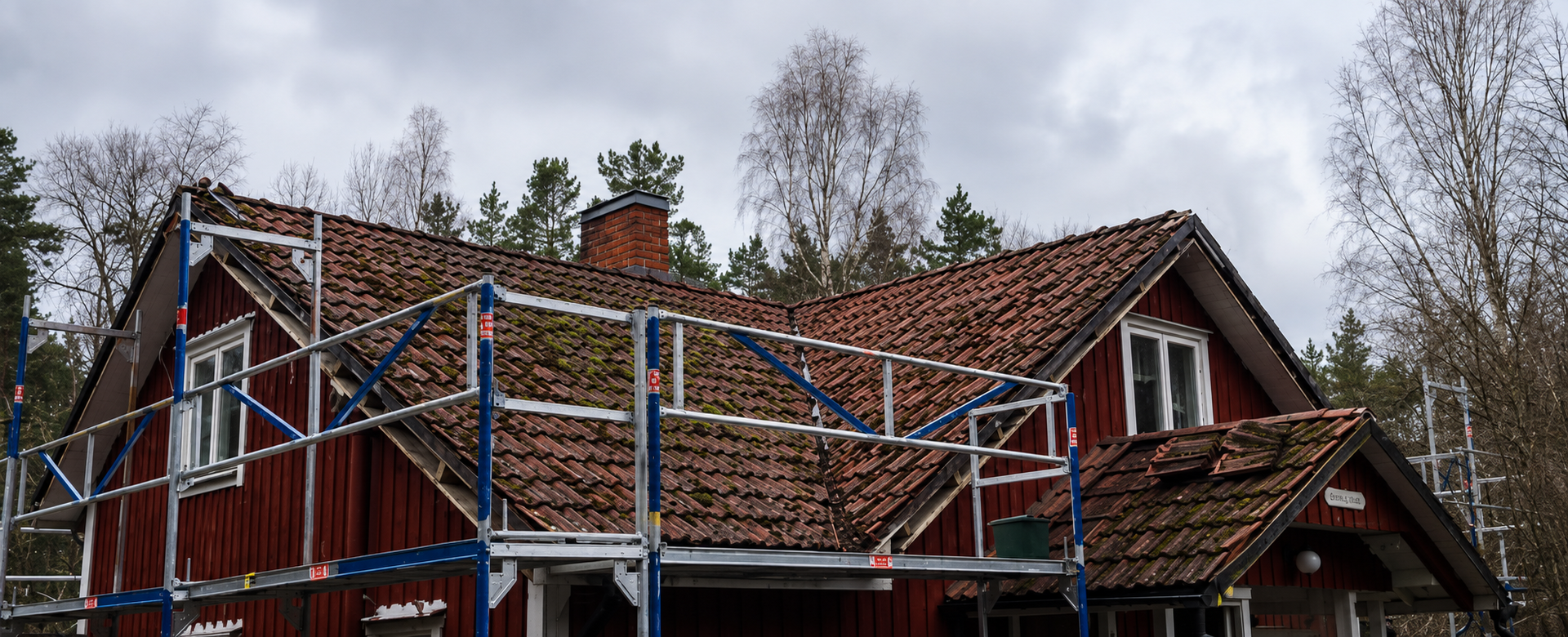 Äldre mossbevuxet tegeltak under renovering med ställning