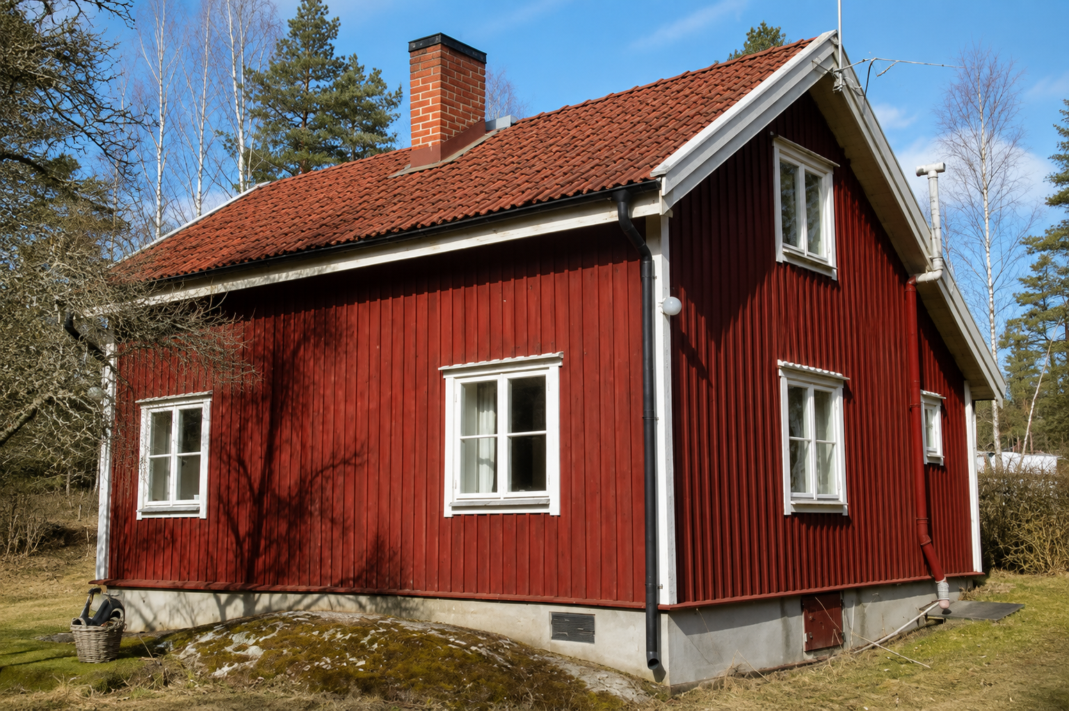 Rött trähus med tegelrött tak och vit fönsterinramning