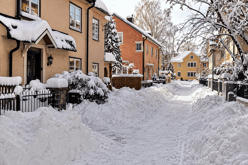 Snötäckt bostadsgata med villor i Stockholm vintertid