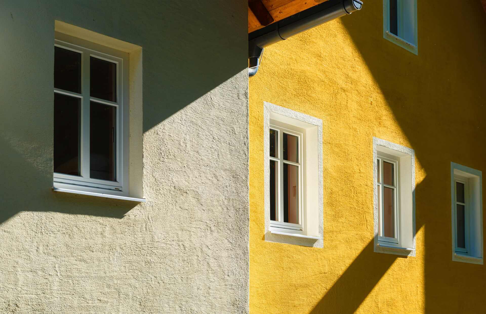 Putsfasad i olika kulörer på hus med vitmålade fönster