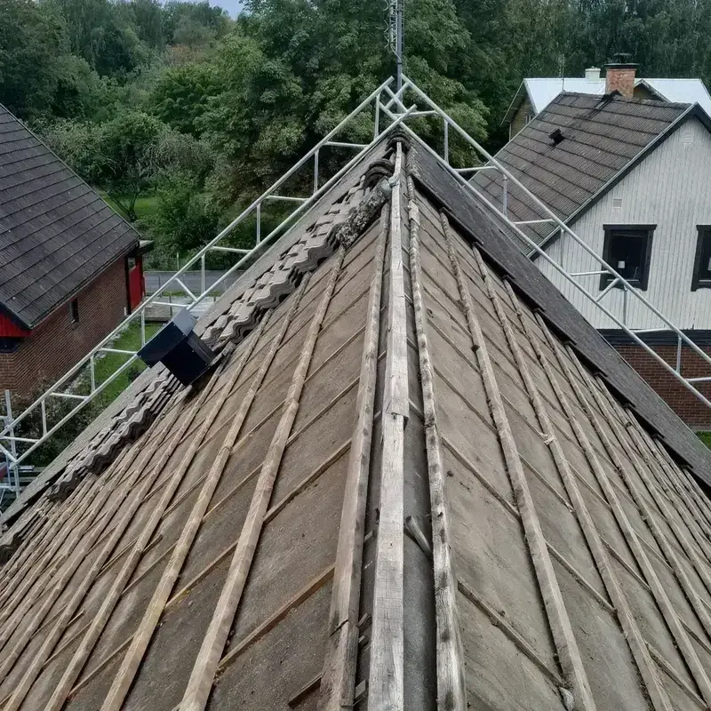 Närbild på rivet tak med exponerad råspont och takläkt längs nocken under pågående takbyte