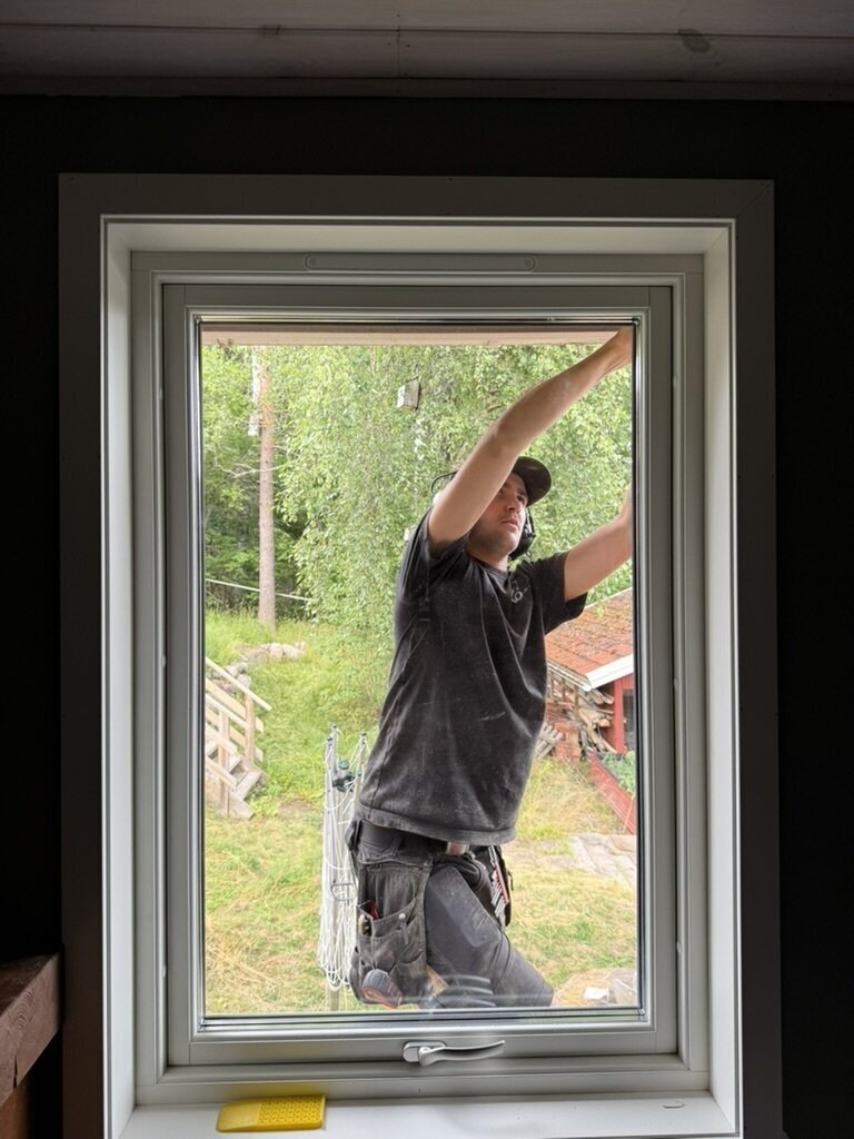 Montör som monterar nytt fönster, fotograferat inifrån huset