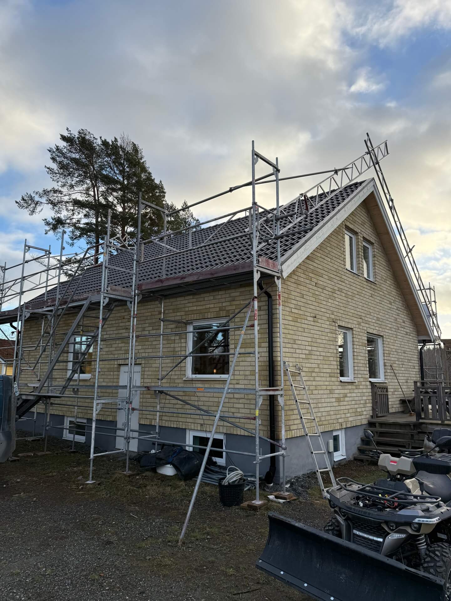Villa med tegelfasad och byggnadsställning under pågående takarbete