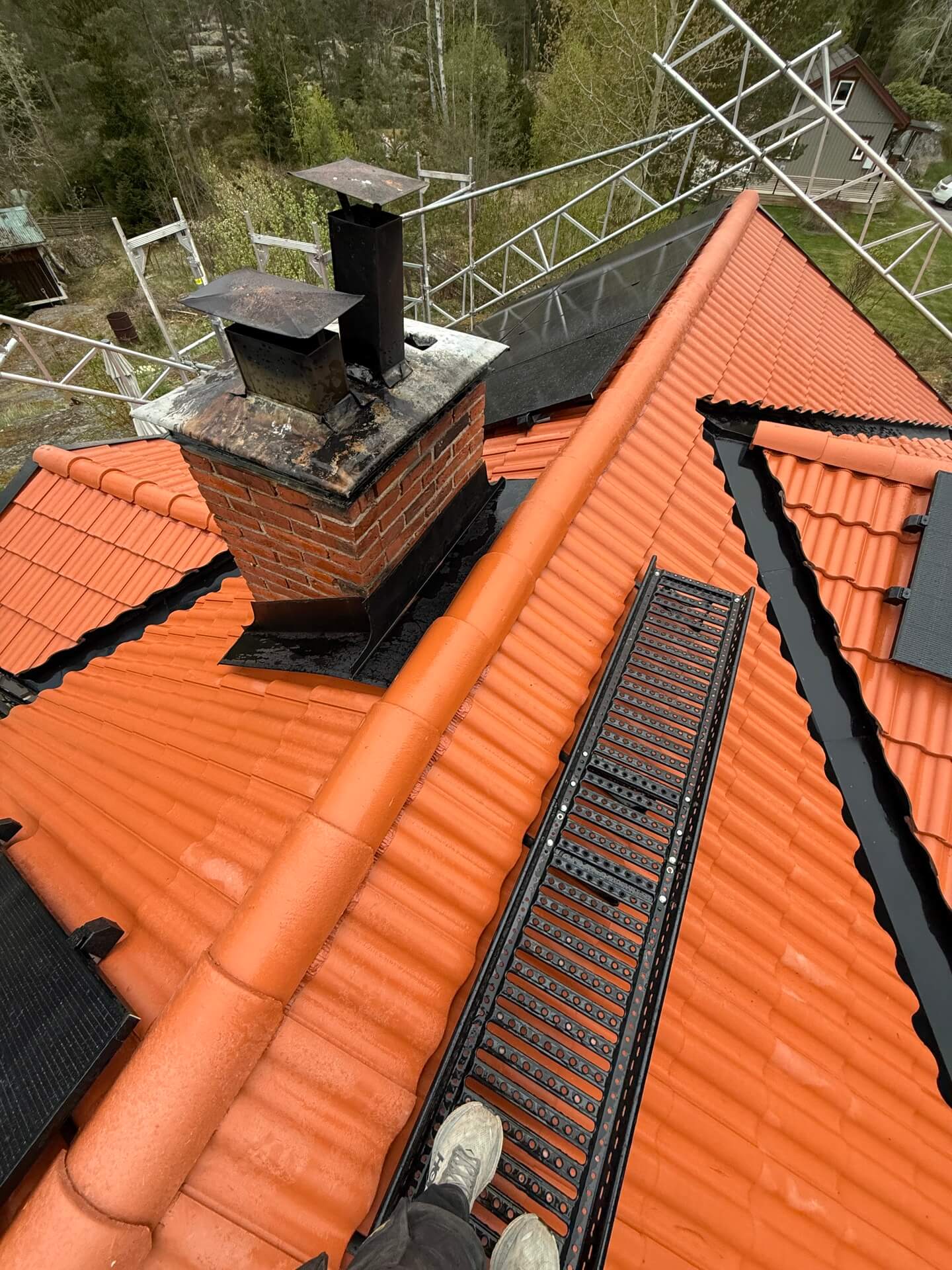 Nylagt orange tegeltak med tegelskorsten och monterad takstege