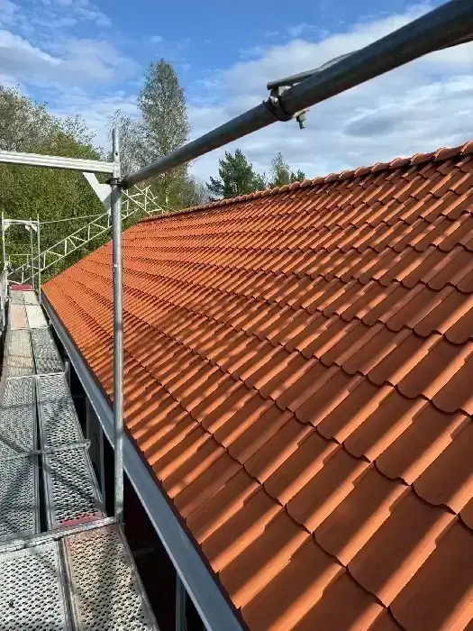 Nylagt tegeltak i orange-röd nyans med byggnadsställning