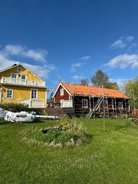 Gul och röd villa med nylagt tegeltak, fotograferad från annan vinkel