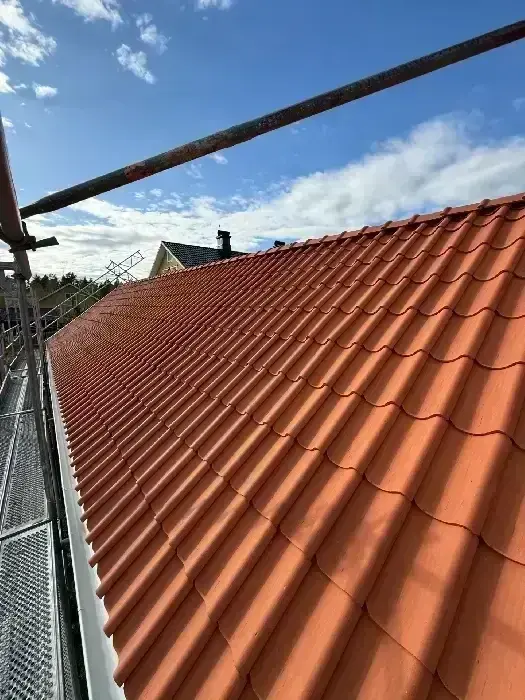 Nylagt rödbrunt tegeltak sett i vidvinkel, med skorsten synlig i bakgrunden