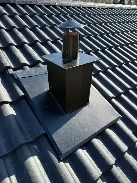 Svart plåtgenomföring för ventilation på nylagt grått tegeltak