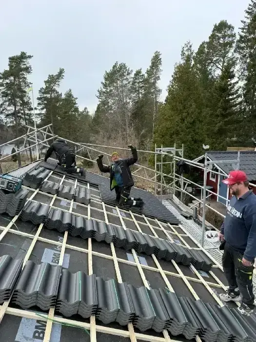 Montörer som lägger tegelpannor på tak under pågående montage