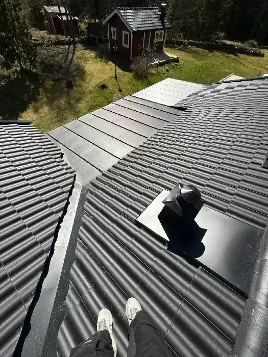 Nylagt grått tegeltak med ventilationshuv vid valmat takparti