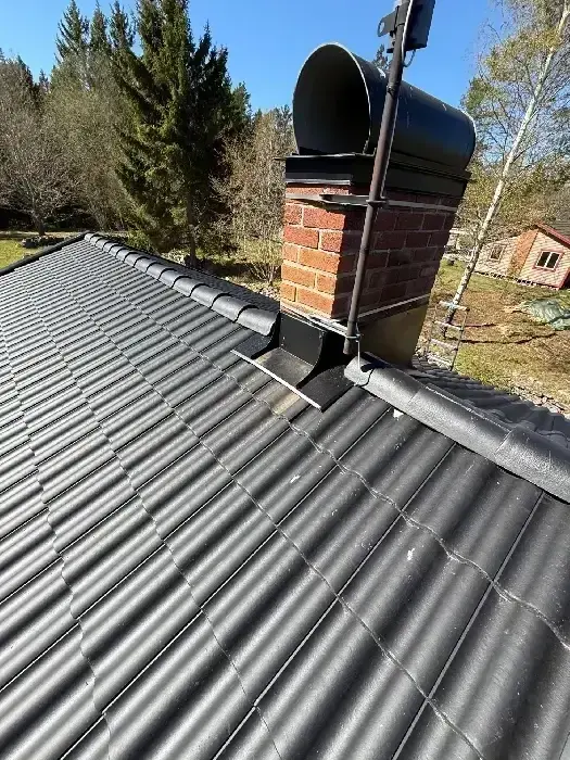 Nylagt svart tegeltak med tegelskorsten i förgrunden