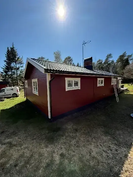 Rödmålad villa sett från sidan, med tegeltak och skorsten