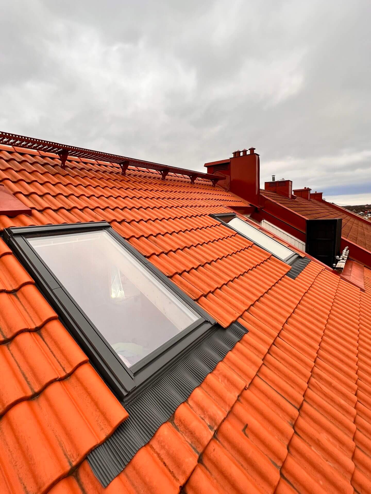 Två Velux takfönster monterade i rött tegeltäckt tak sett utifrån