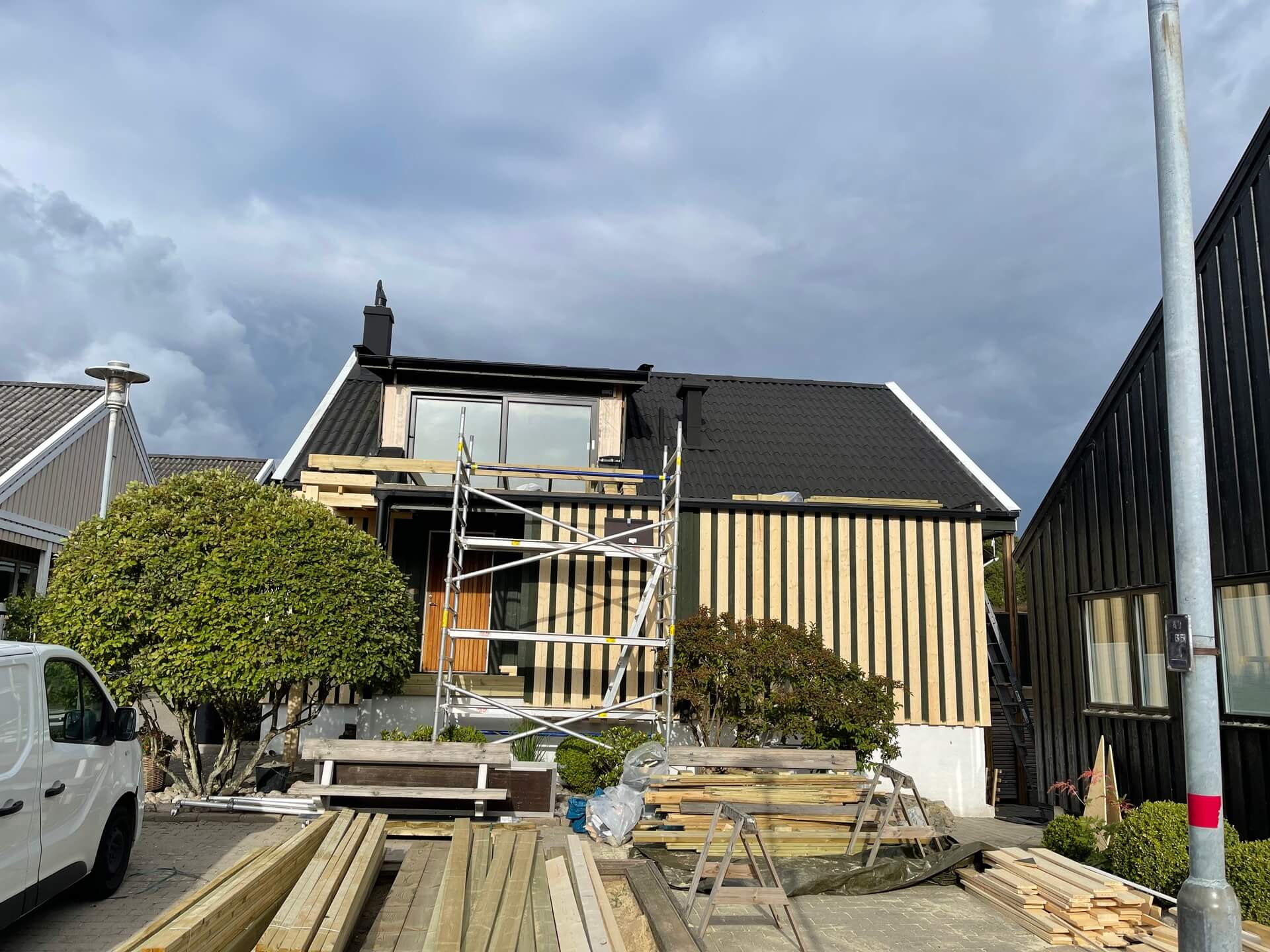 Mörk villa med ny träpanelfasad och ställning under pågående byggnation