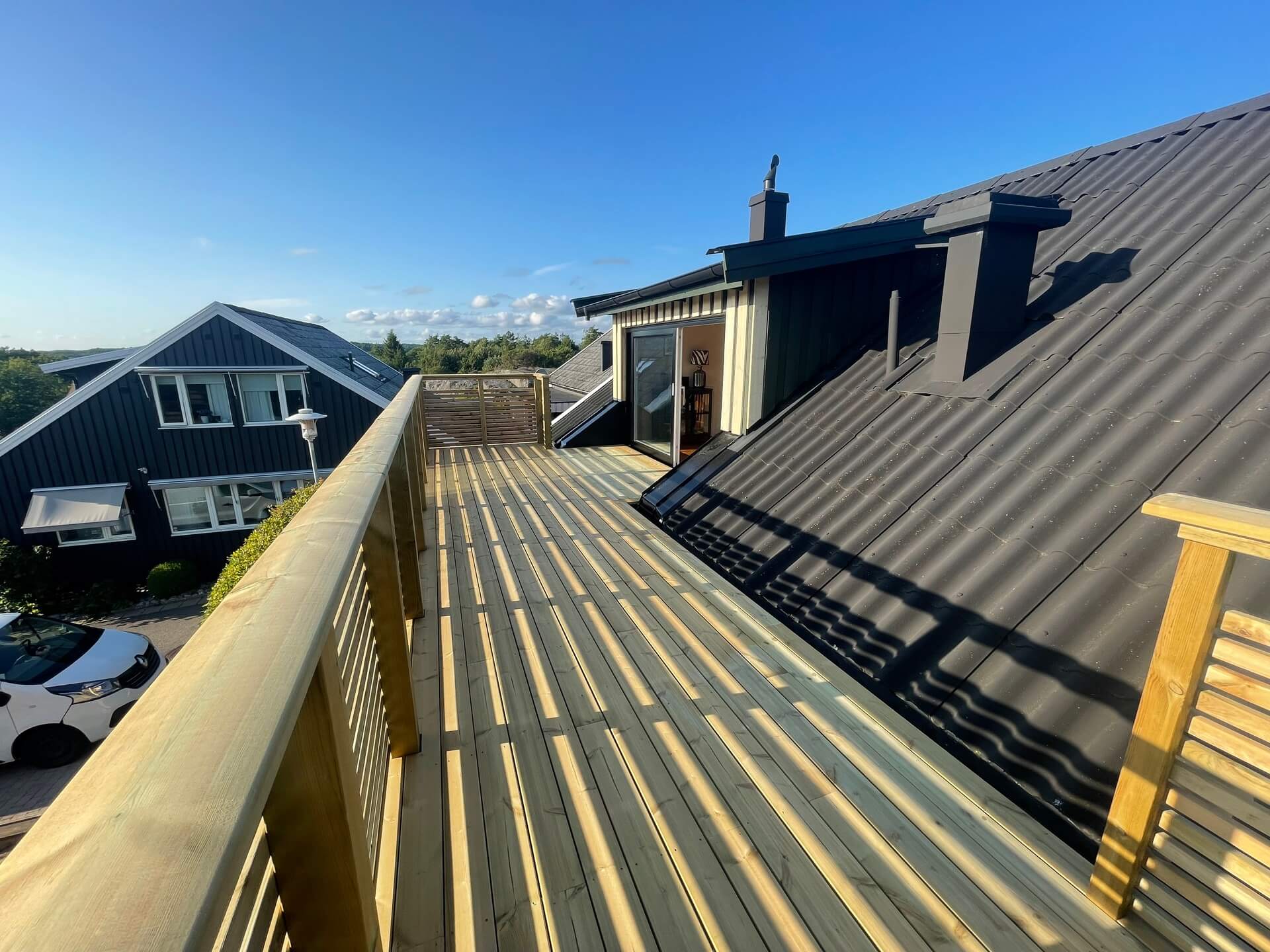 Takterrass med trädäck och träräcke med vid utsikt över villaområde och hav