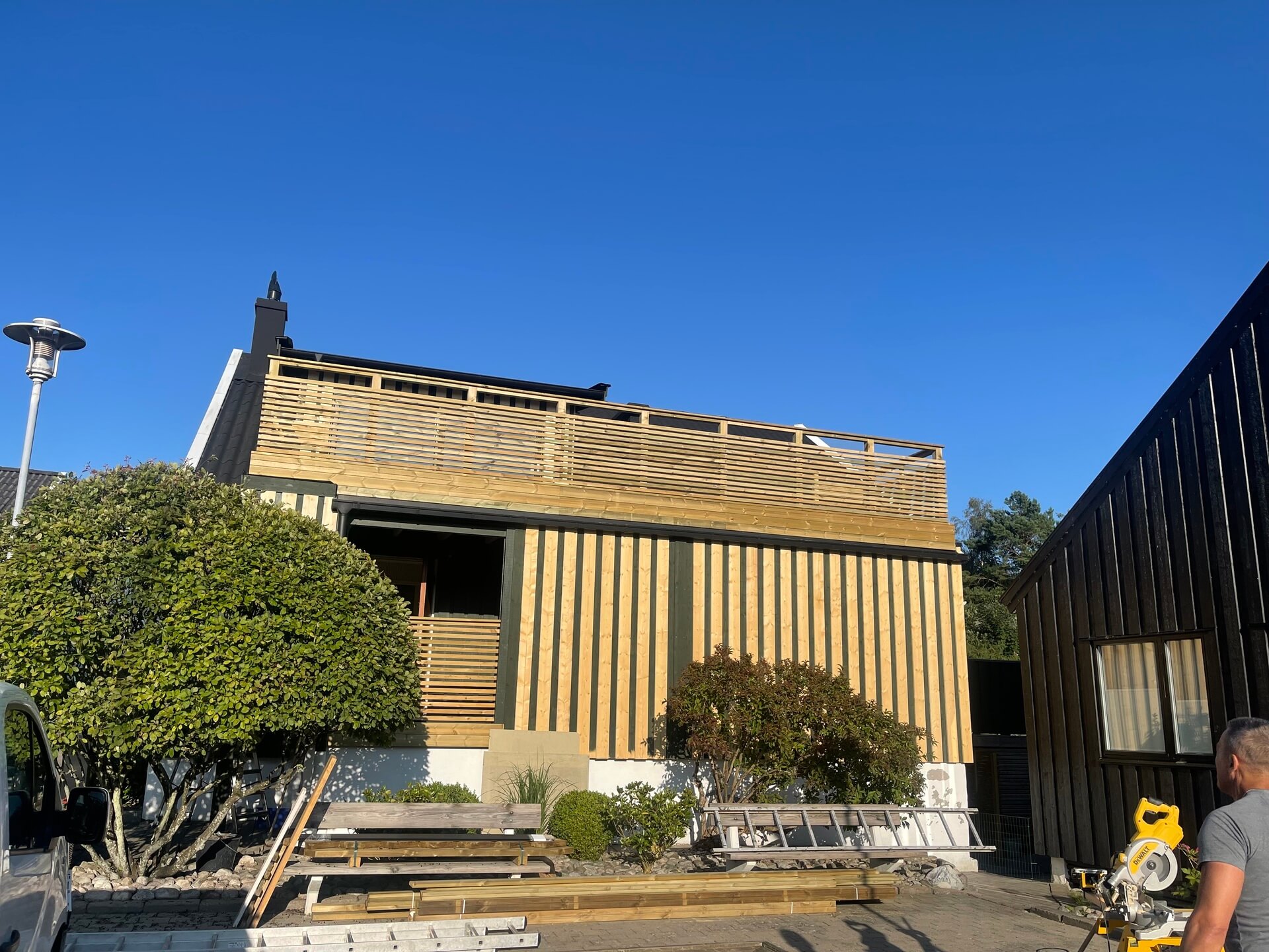 Villa med ny vertikal träpanelfasad och takterrass under slutförande