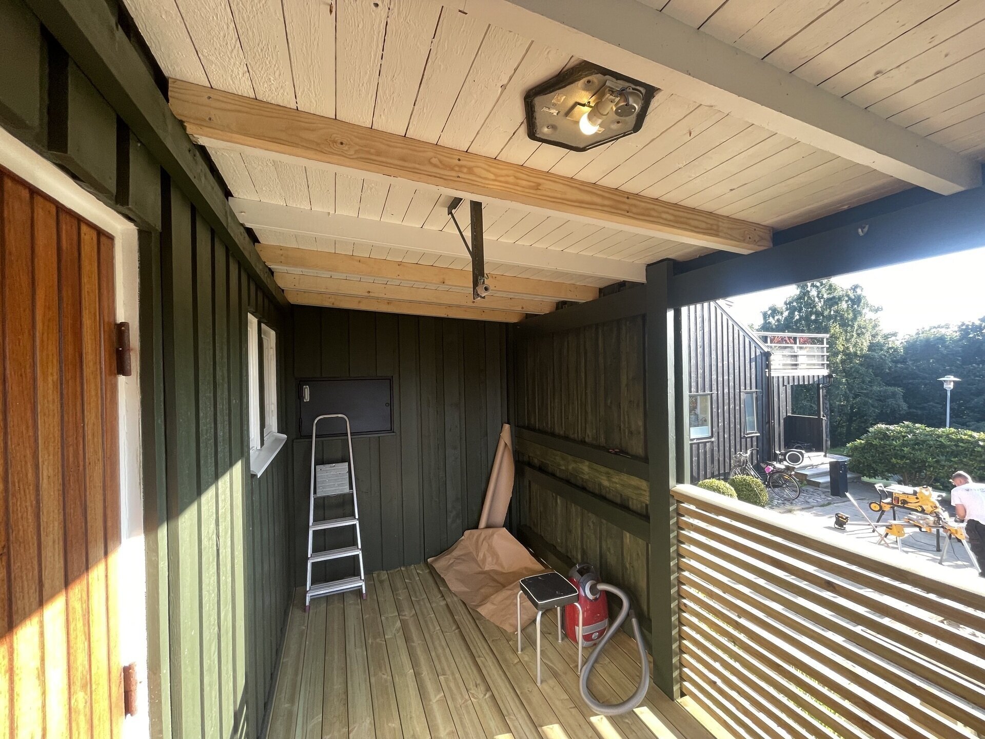 Öppen veranda med trätak och panel under pågående arbete