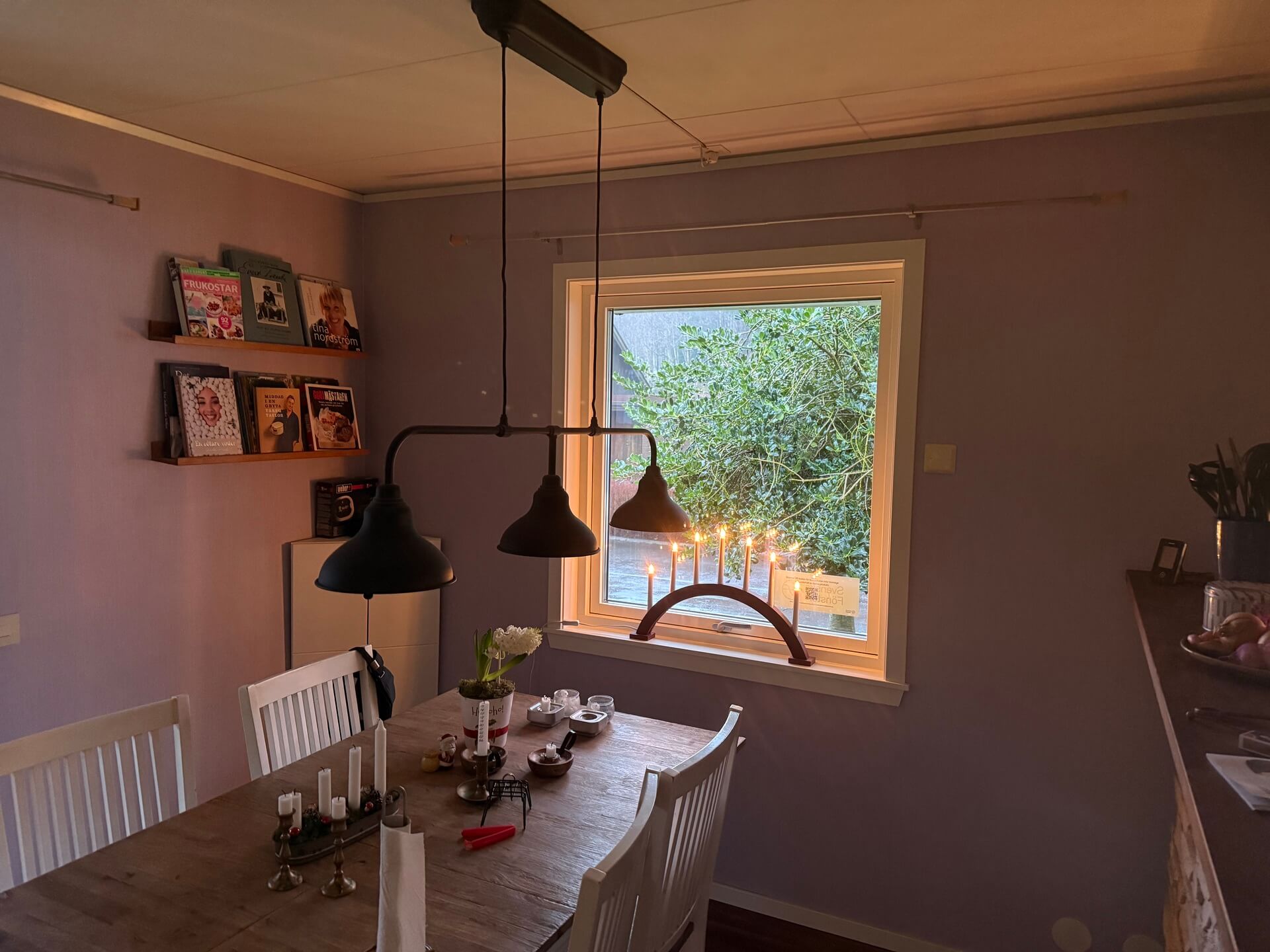 Nyinstallerat fönster med träkarm i matrum med industrilampa och utsikt mot trädgård