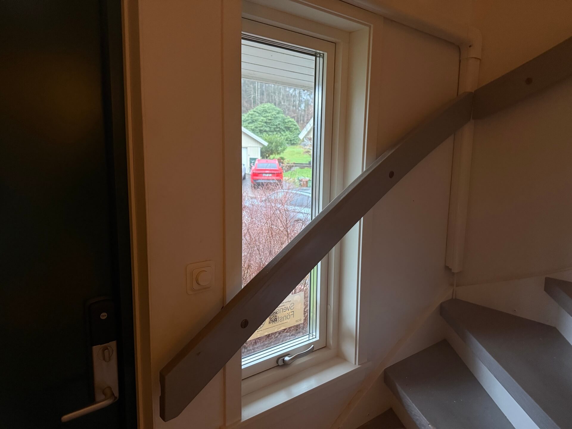 Nyinstallerat fönster med vit karm vid trappa i snedtaksrum