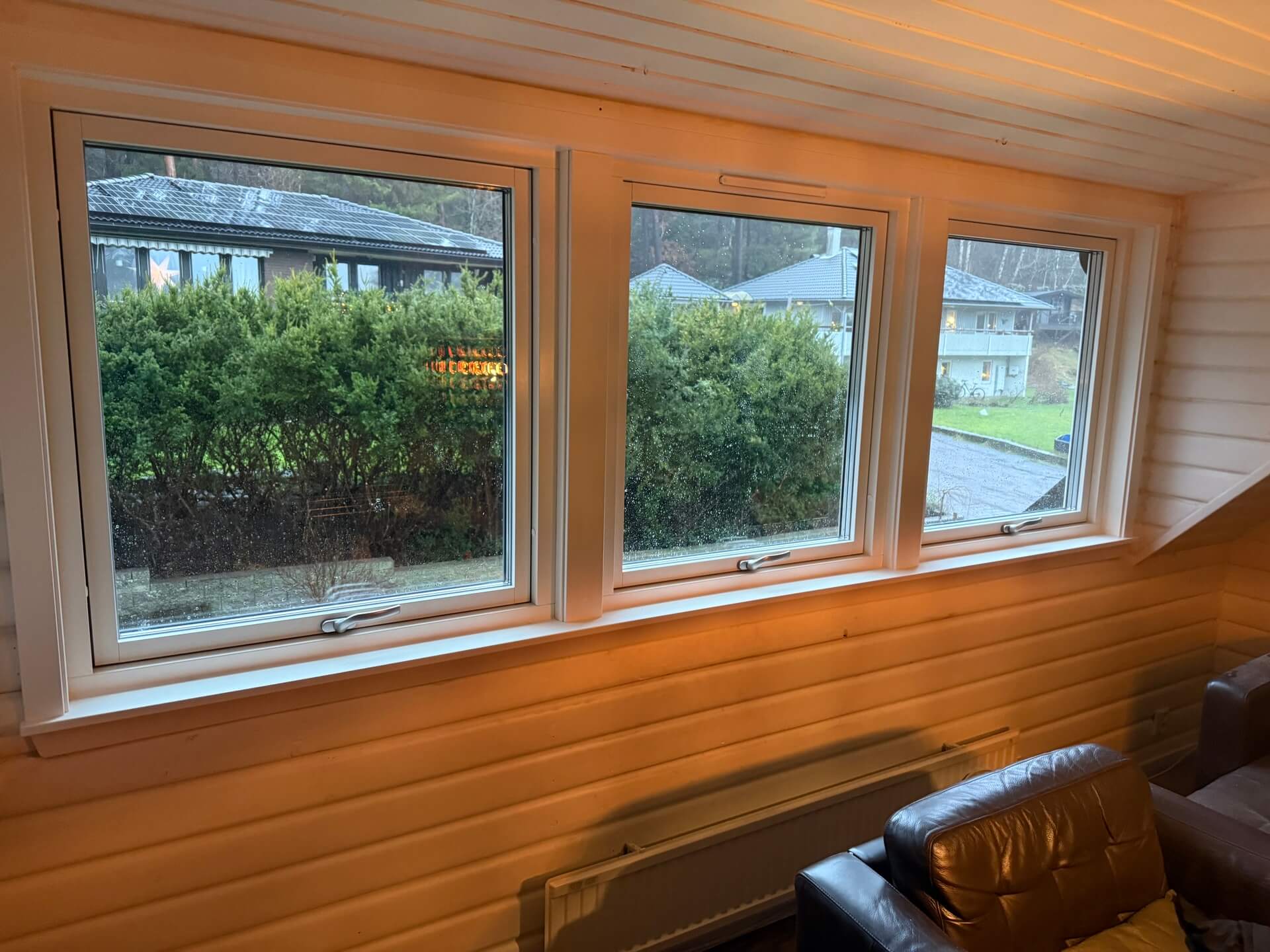 Tre nyinstallerade vridfönster i rad med vit karm i rum med träpanel