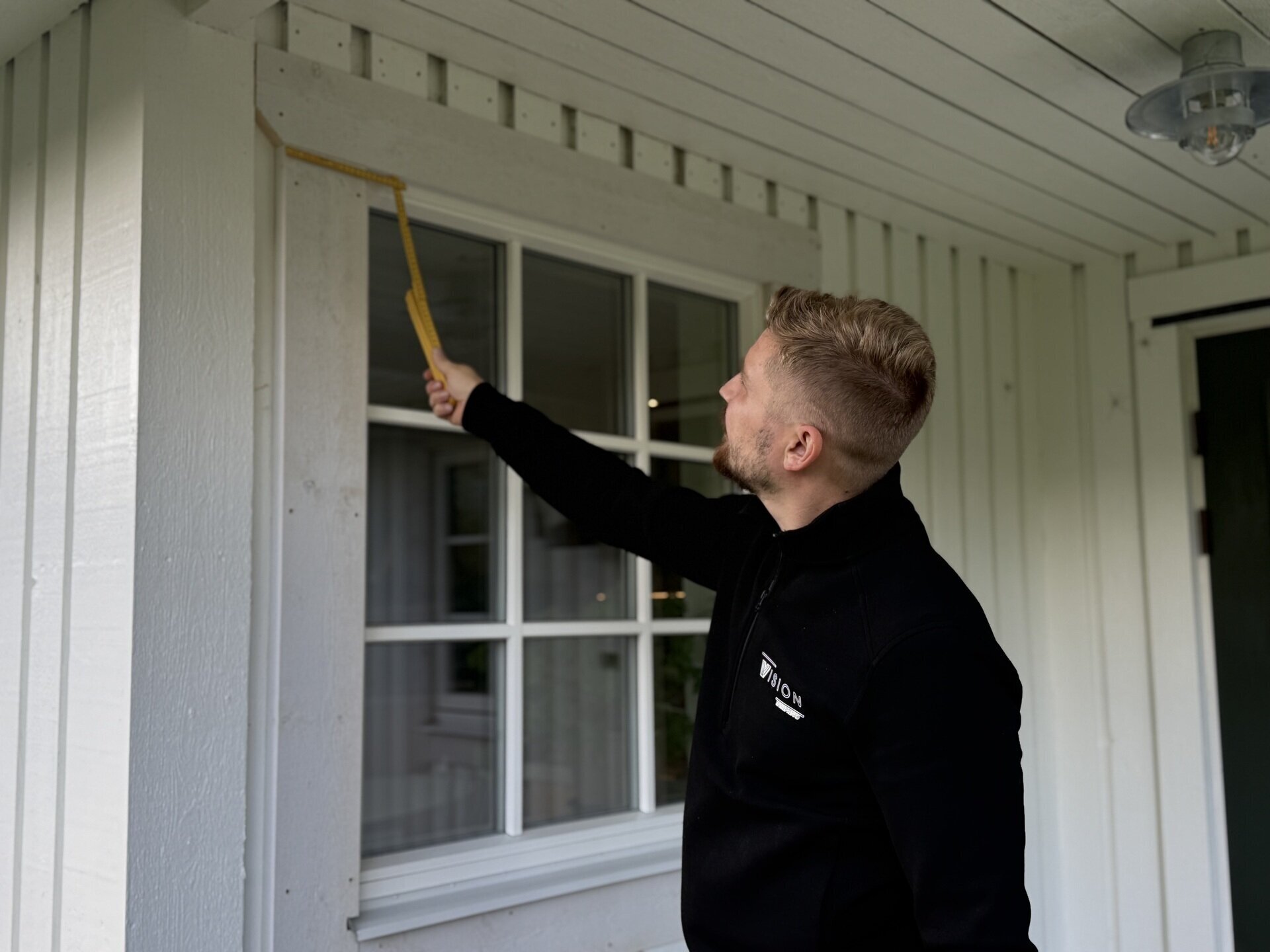 Montör från Vision Entreprenad tätar utvändigt runt spröjsade fönster på vit fasad