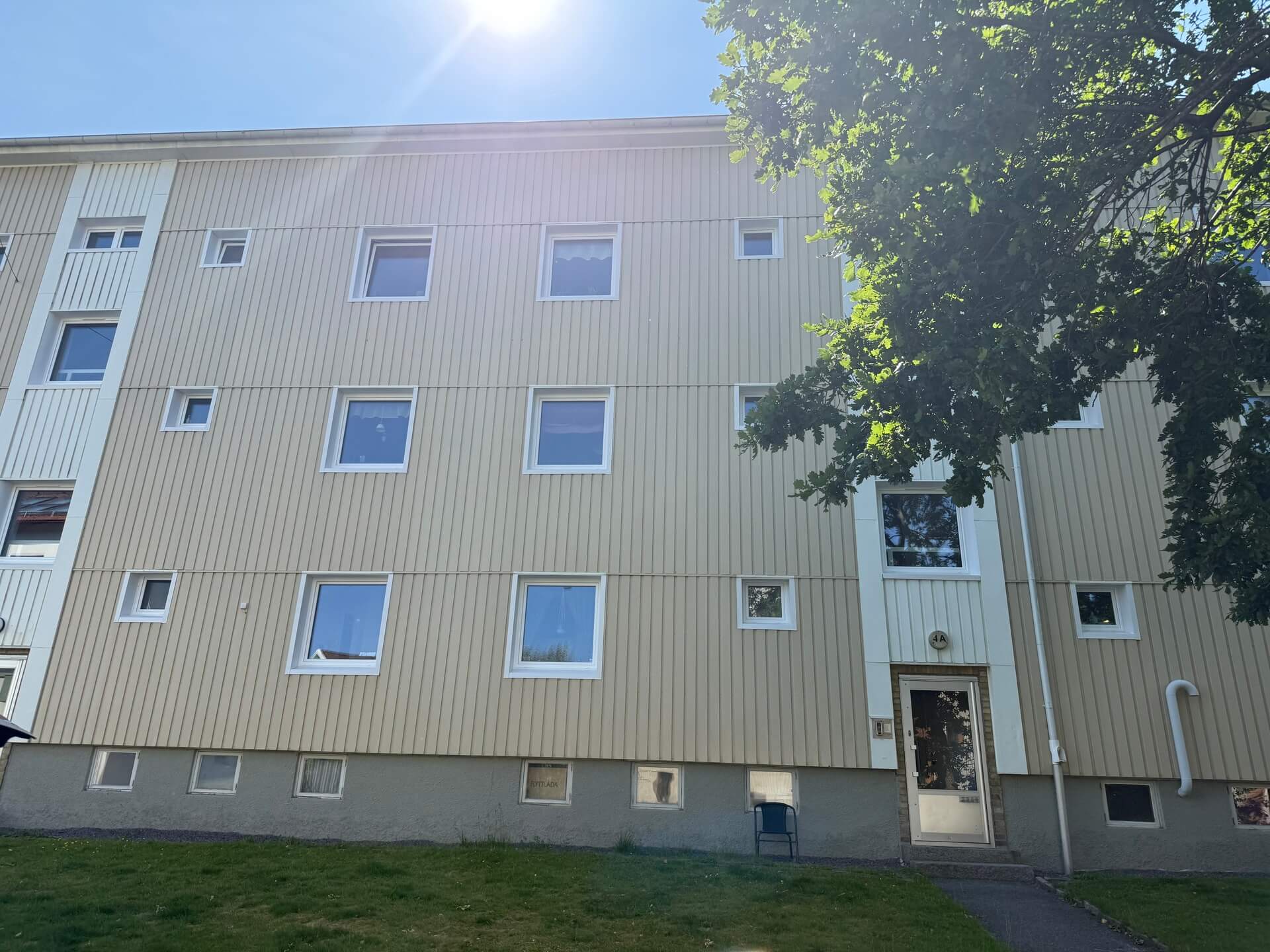 Närbild på flerbostadshus med nyinstallerade vita fönster i varierande storlekar