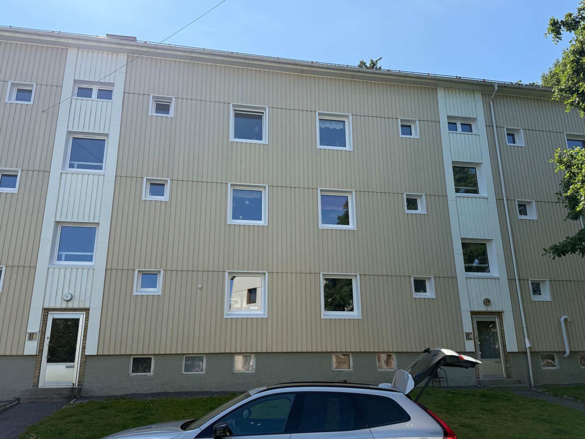 Flerbostadshus med nyinstallerade vita fönster och ljus vertikal träpanelfasad